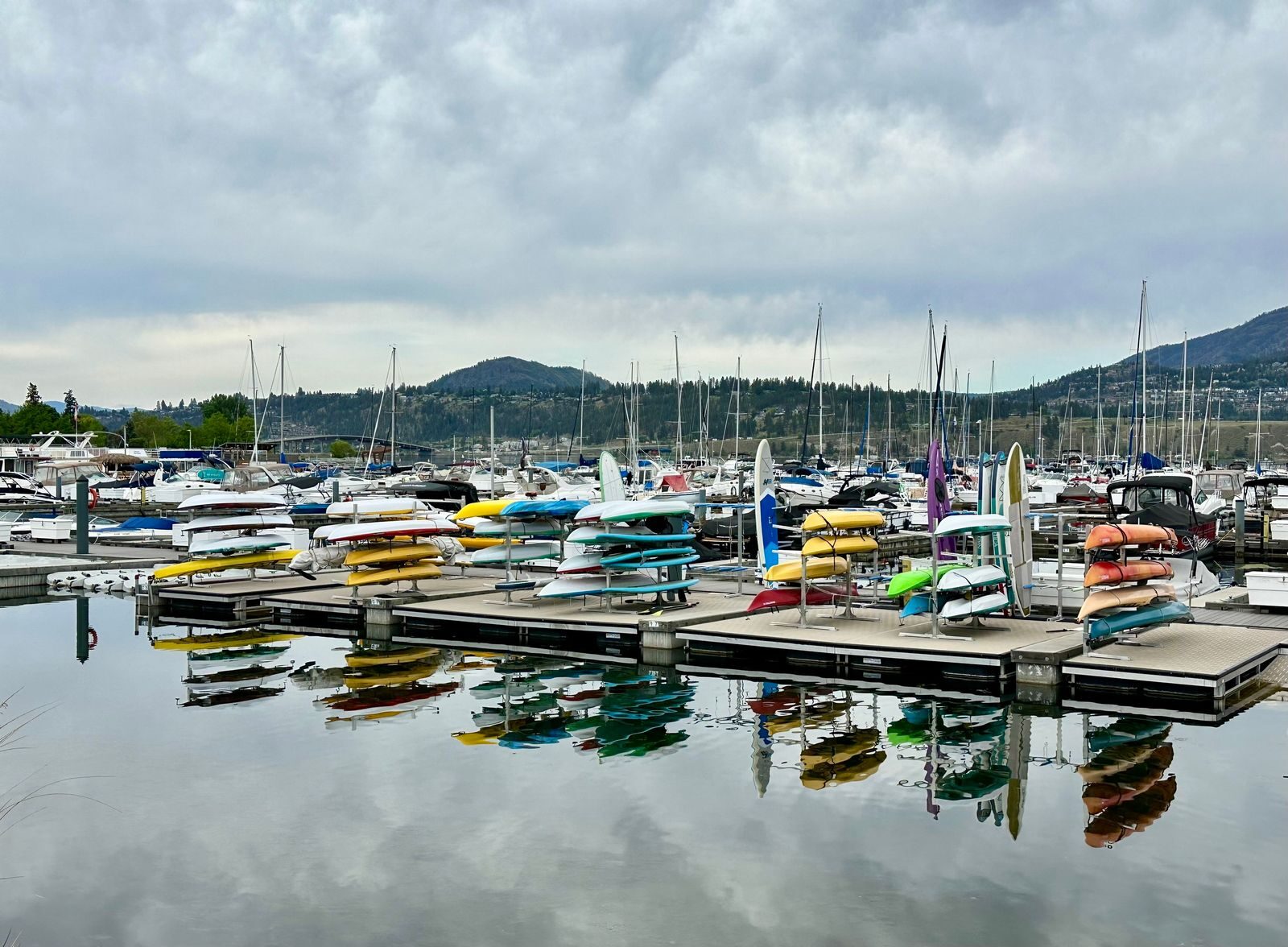 Kayaks and boats in a Kelowna marina with mountains behind